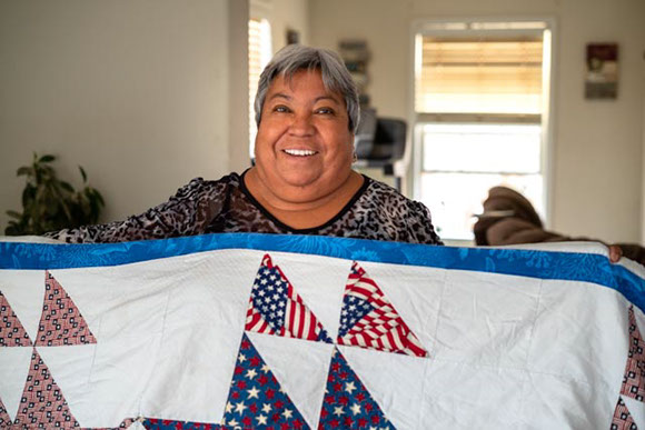 Maria Ignacia Sanchez smiles as she holds a boat quilt she made for her daughter, Maria Ureste. Photo by Alex Labry